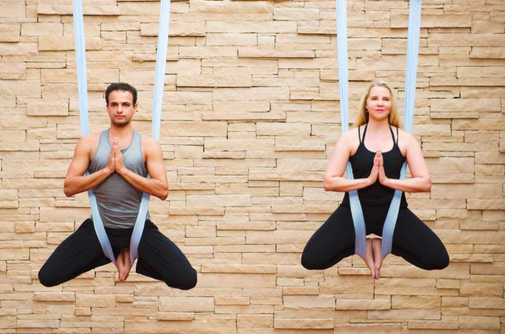 man and woman practising aerial yoga