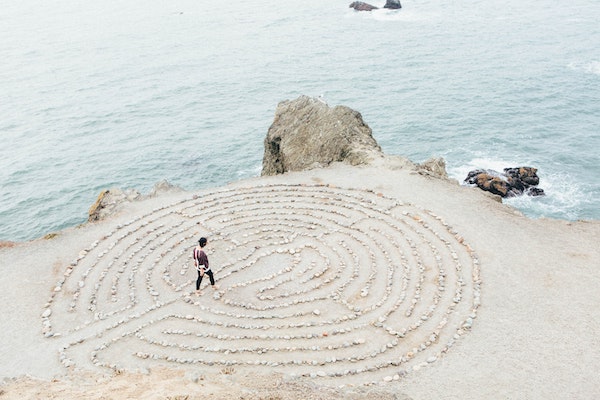 a person walking at the beach inside a maze created with rocks