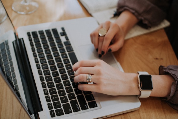 a girl with a smartwatch working on her laptop